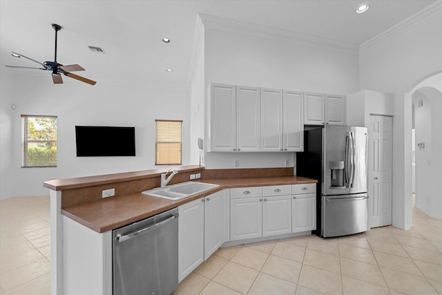 kitchen featuring white cabinets, sink, light tile patterned floors, a towering ceiling, and appliances with stainless steel finishes