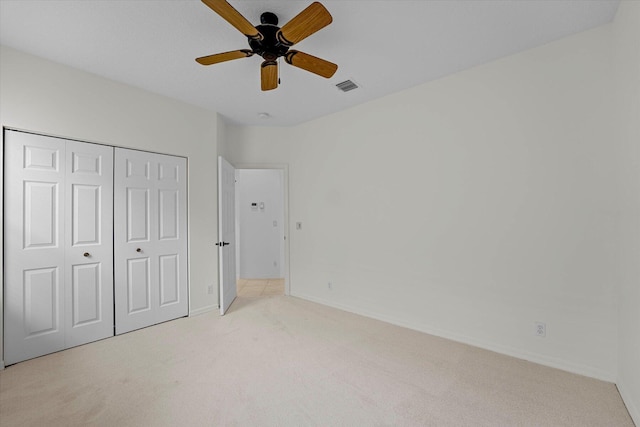 unfurnished bedroom featuring ceiling fan, a closet, and light colored carpet