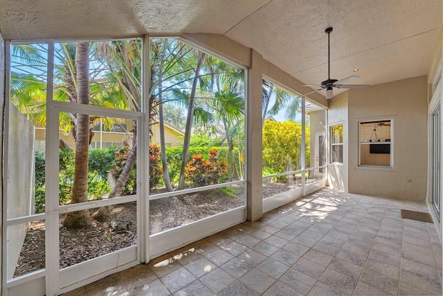 unfurnished sunroom featuring ceiling fan, a wealth of natural light, and vaulted ceiling