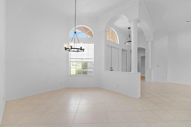 tiled spare room featuring decorative columns, crown molding, and a notable chandelier