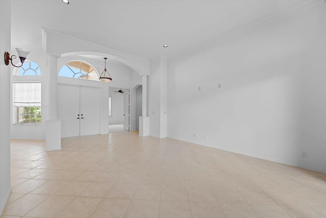 entryway featuring crown molding, a towering ceiling, and light tile patterned floors