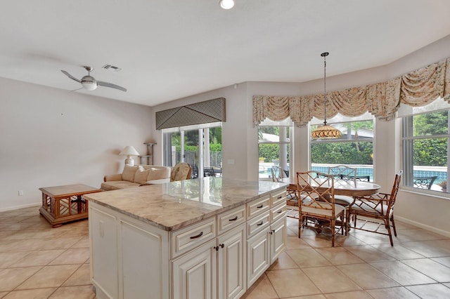 kitchen with pendant lighting, ceiling fan, a kitchen island, and light tile patterned floors