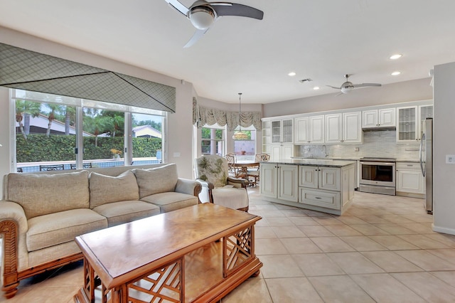 tiled living room featuring ceiling fan with notable chandelier