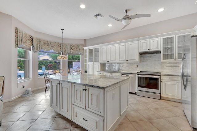 kitchen featuring a center island, white cabinets, ceiling fan, light tile patterned flooring, and stainless steel appliances