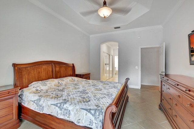 bedroom with ceiling fan, ornamental molding, ensuite bathroom, and a tray ceiling