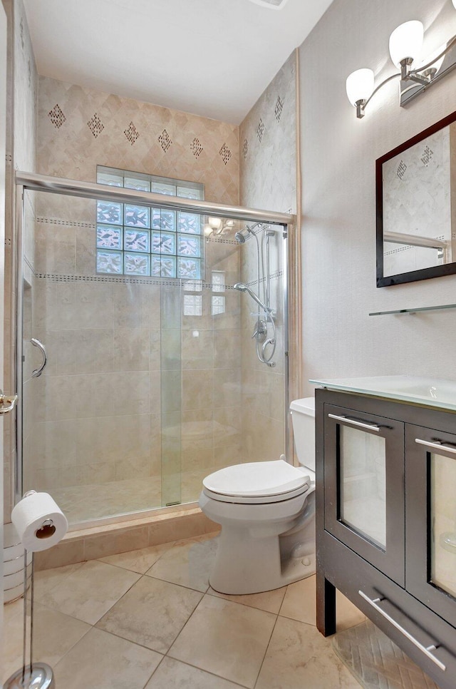 bathroom with toilet, tile patterned flooring, vanity, and walk in shower