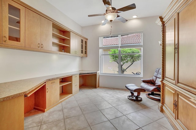 interior space featuring ceiling fan, light brown cabinets, light tile patterned floors, and built in desk