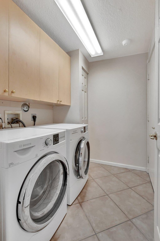 laundry area featuring cabinets, a textured ceiling, washer and dryer, and light tile patterned flooring