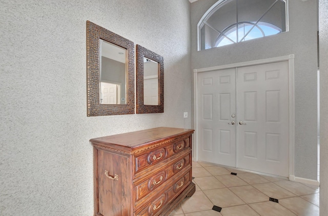 foyer with a towering ceiling and light tile patterned flooring