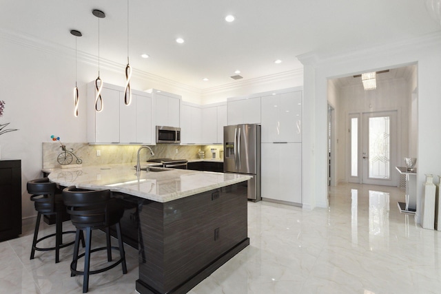 kitchen featuring kitchen peninsula, pendant lighting, a kitchen bar, white cabinets, and appliances with stainless steel finishes