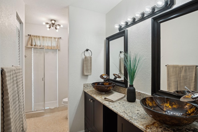 bathroom featuring tile patterned flooring, vanity, toilet, and a shower with door