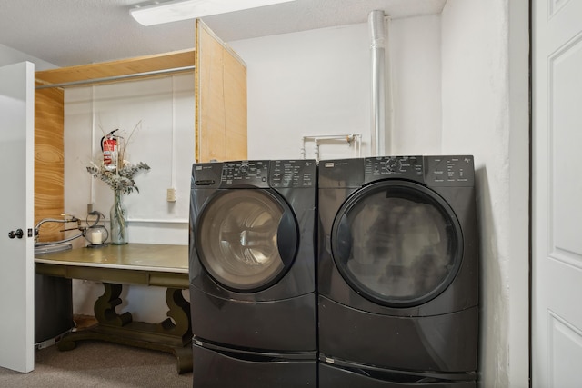 clothes washing area featuring washing machine and clothes dryer, carpet flooring, and a textured ceiling