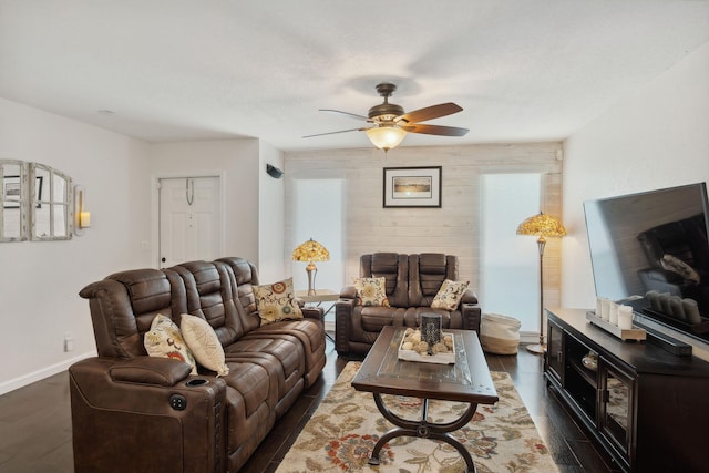 living room with a wealth of natural light, ceiling fan, and dark wood-type flooring