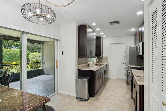 kitchen featuring light stone countertops, dark brown cabinets, and appliances with stainless steel finishes