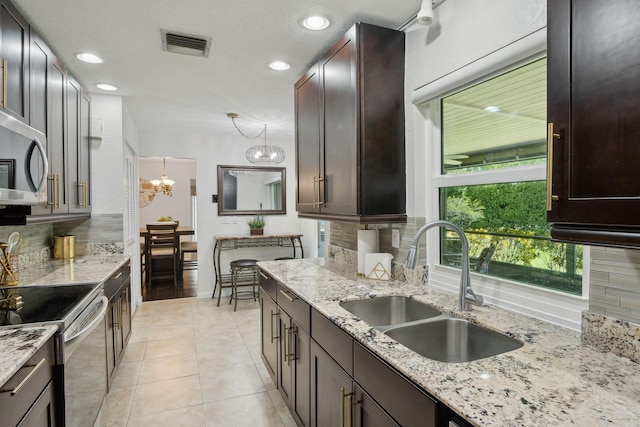 kitchen with backsplash, sink, hanging light fixtures, light stone counters, and a chandelier