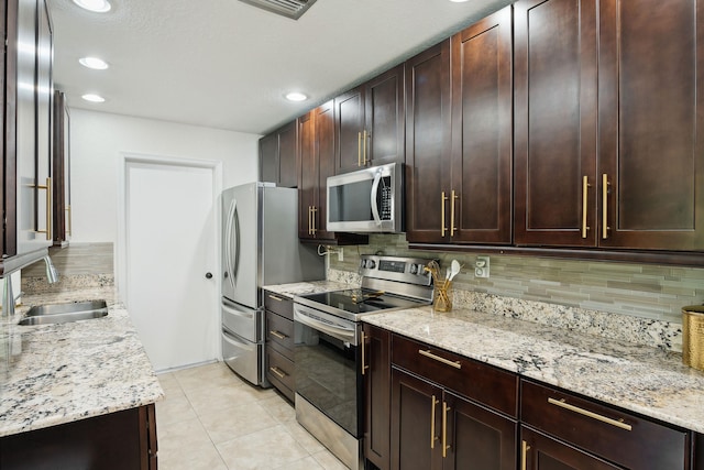 kitchen featuring light stone countertops, appliances with stainless steel finishes, backsplash, and sink