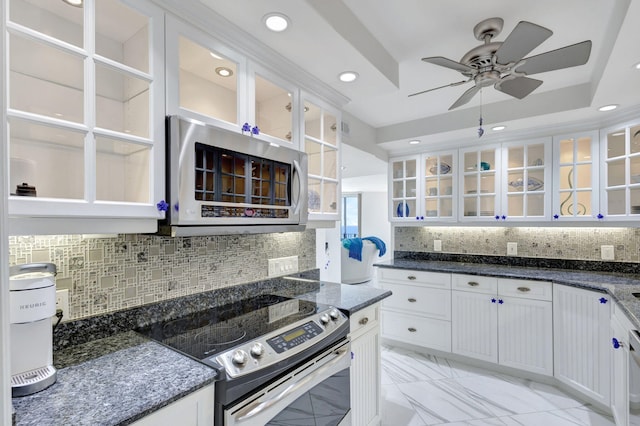 kitchen with white cabinets, ceiling fan, dark stone countertops, appliances with stainless steel finishes, and tasteful backsplash