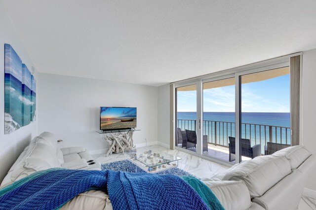 living room with expansive windows, a water view, and a textured ceiling