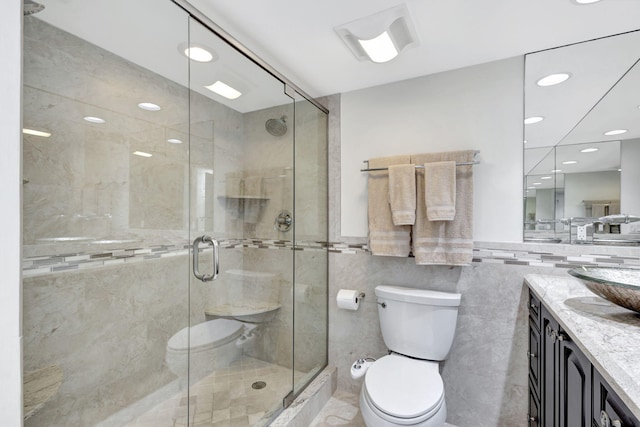 bathroom with vanity, a shower with shower door, tile walls, and toilet