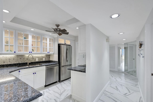 kitchen featuring sink, backsplash, dark stone countertops, white cabinets, and appliances with stainless steel finishes