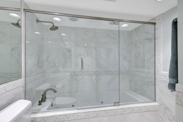 bathroom featuring toilet, combined bath / shower with glass door, and tile walls