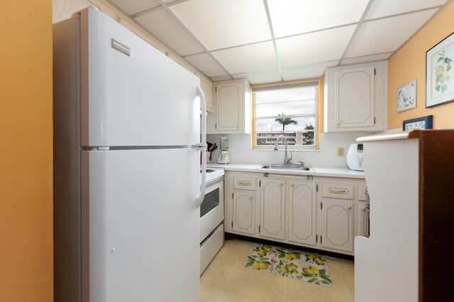 kitchen featuring sink, light tile flooring, white appliances, and a paneled ceiling