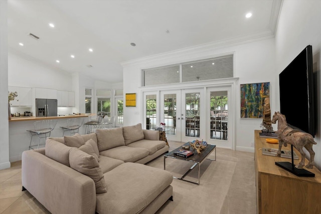 living room featuring french doors, light tile patterned floors, ornamental molding, and a high ceiling