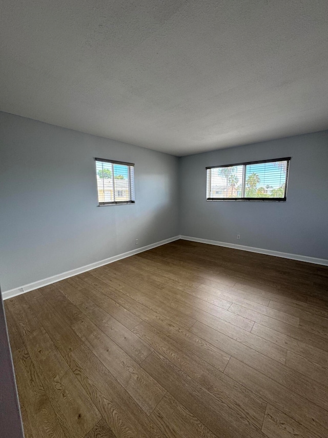 spare room featuring a textured ceiling and dark hardwood / wood-style flooring