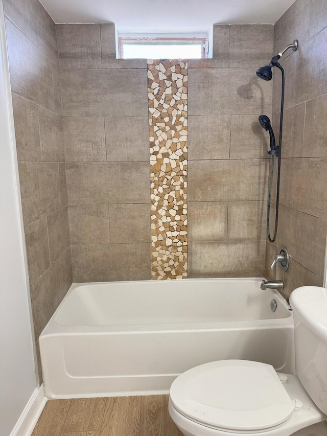 bathroom featuring tiled shower / bath combo, hardwood / wood-style floors, and toilet