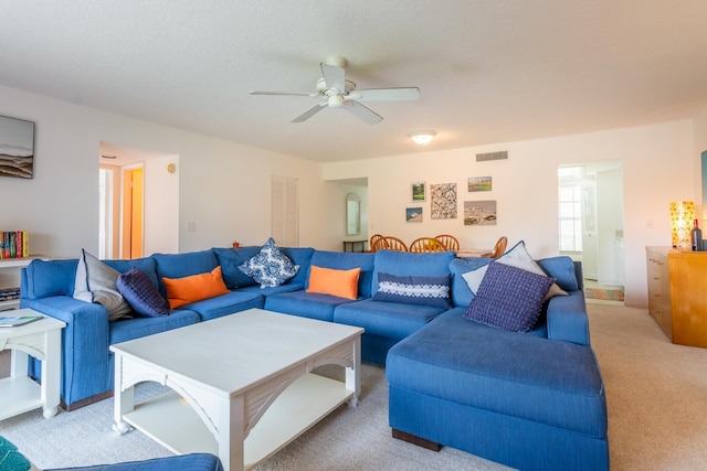 carpeted living room featuring ceiling fan and a textured ceiling