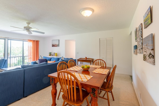 carpeted dining room featuring ceiling fan and a textured ceiling