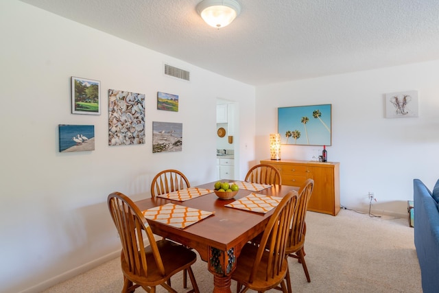 dining room featuring light carpet and a textured ceiling