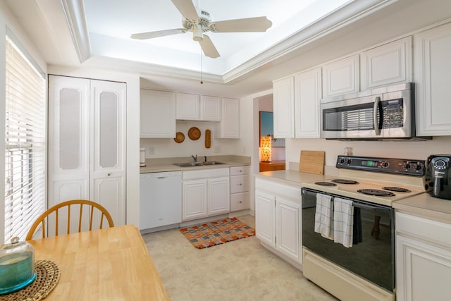 kitchen with white appliances, white cabinets, a raised ceiling, crown molding, and sink