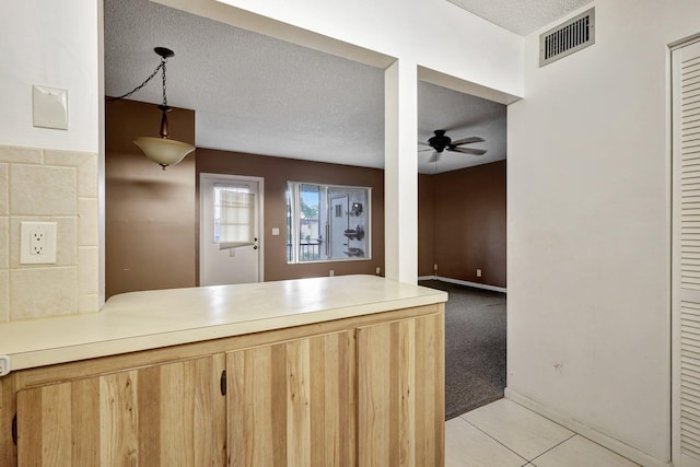 kitchen featuring light carpet, a textured ceiling, ceiling fan, and light brown cabinetry