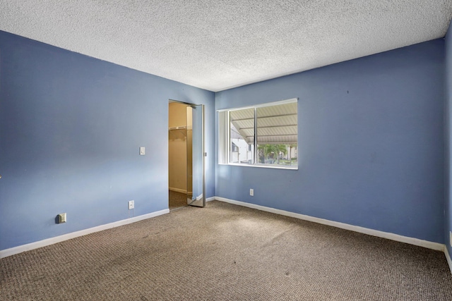 empty room with carpet and a textured ceiling