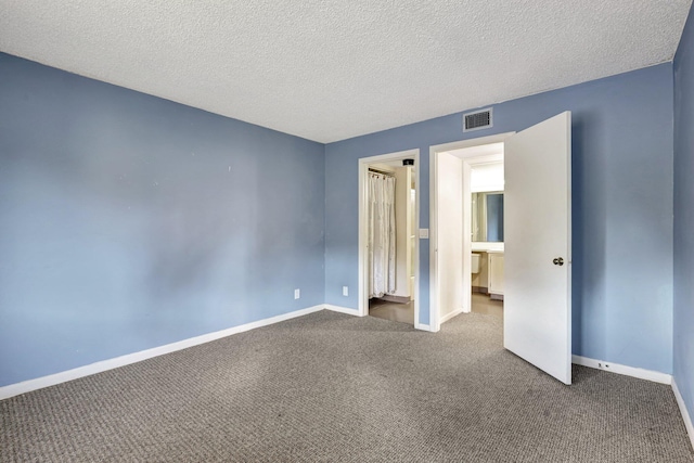 unfurnished bedroom with a textured ceiling and dark carpet