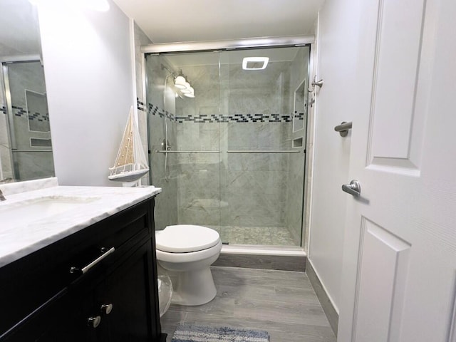 bathroom featuring vanity, toilet, wood-type flooring, and an enclosed shower