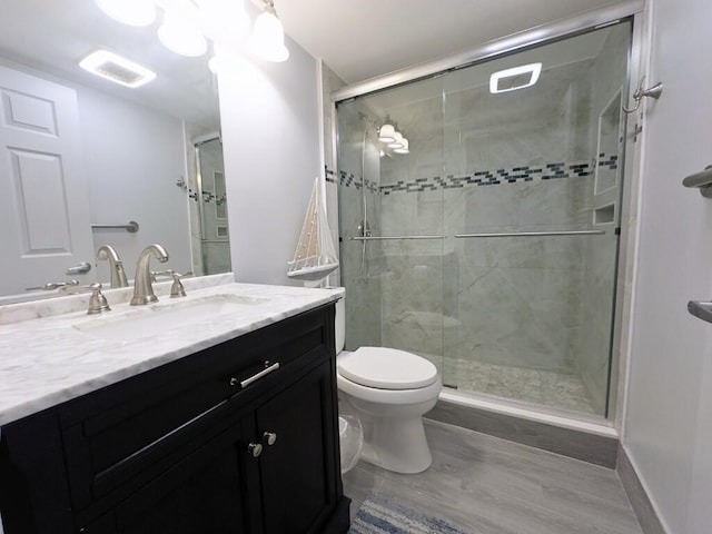 bathroom featuring vanity, toilet, walk in shower, and hardwood / wood-style floors