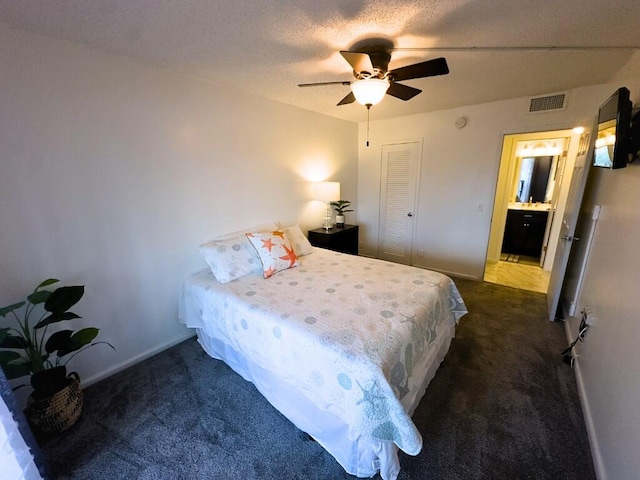 carpeted bedroom with a textured ceiling, ensuite bathroom, a closet, and ceiling fan