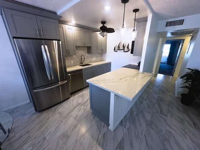 kitchen featuring light stone countertops, sink, stainless steel appliances, pendant lighting, and decorative backsplash