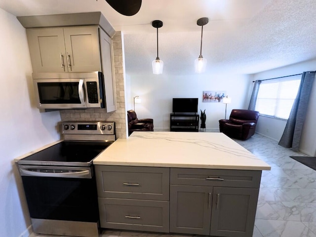 kitchen featuring light stone countertops, pendant lighting, appliances with stainless steel finishes, and gray cabinetry