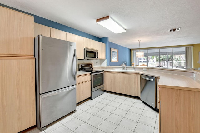 kitchen with stainless steel appliances, light brown cabinetry, decorative light fixtures, sink, and light tile floors