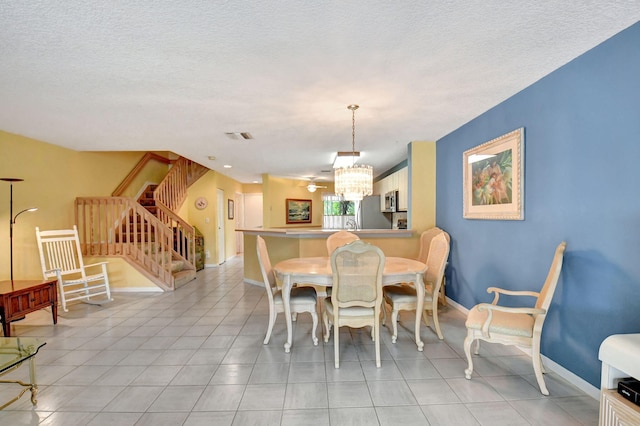 tiled dining room with a chandelier and a textured ceiling