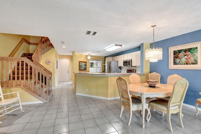 tiled dining room with a textured ceiling and a chandelier