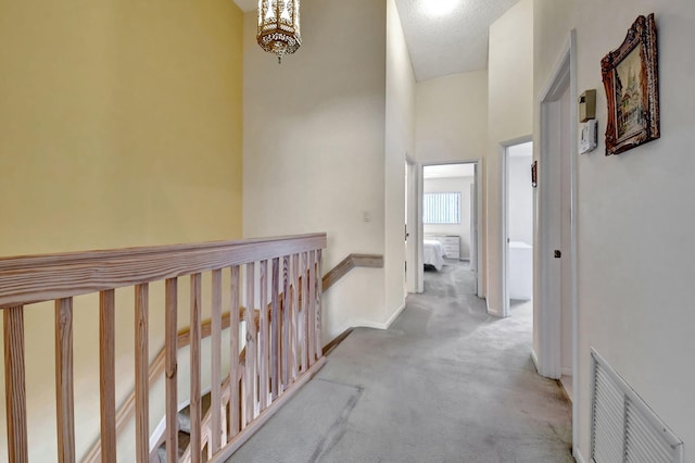 hallway featuring carpet flooring, an inviting chandelier, and high vaulted ceiling