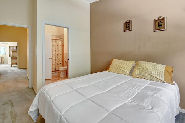 carpeted bedroom with a high ceiling and ensuite bath