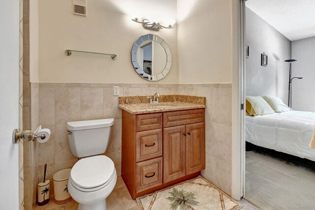 bathroom with tile walls, tile floors, vanity, and toilet