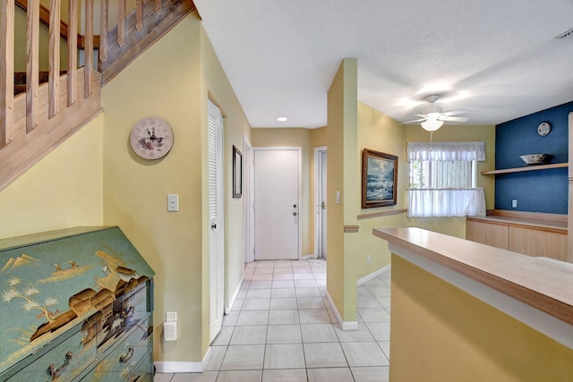 hallway with a textured ceiling and light tile flooring