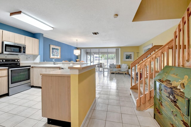 kitchen with light brown cabinets, kitchen peninsula, pendant lighting, light tile floors, and appliances with stainless steel finishes