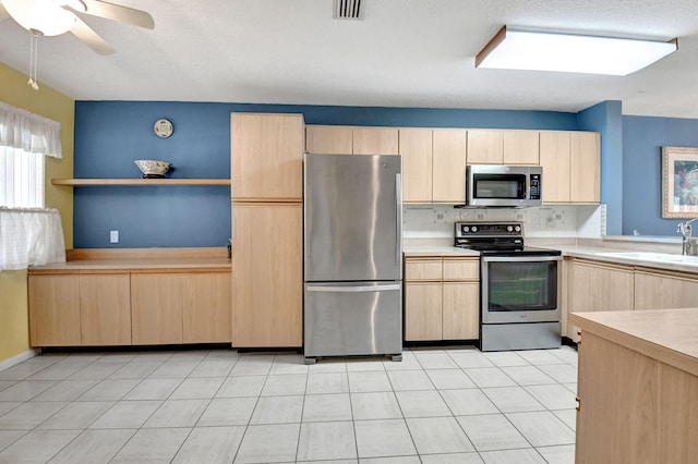 kitchen with stainless steel appliances, ceiling fan, light brown cabinetry, and light tile flooring